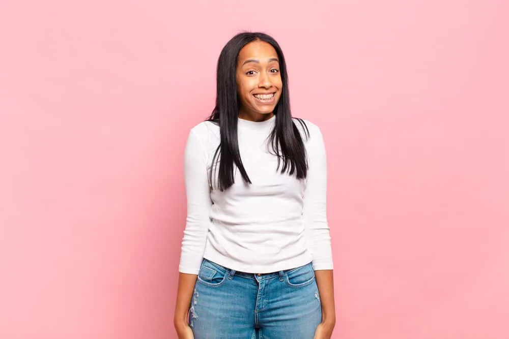 Can You Use Hairspray Before Straightening Your Hair? 2 Adolescent black girl with a goofy smile wearing perfectly straight hair styled with a light hair spray.