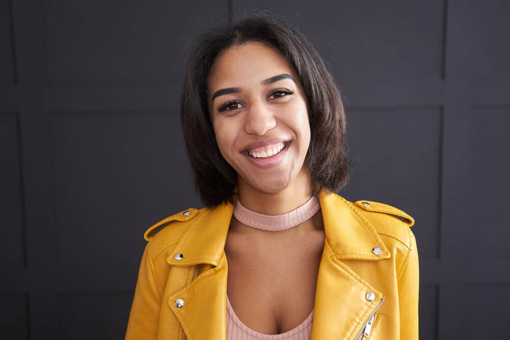 Cute African American female after straightening hair with a good flat iron with an adjustable temperature dial.