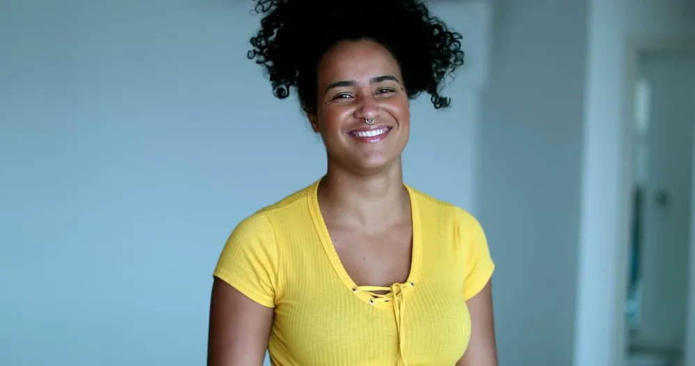 A young black lady wearing a yellow sleep shirt with curly natural hair goes through proper nighttime preparation.