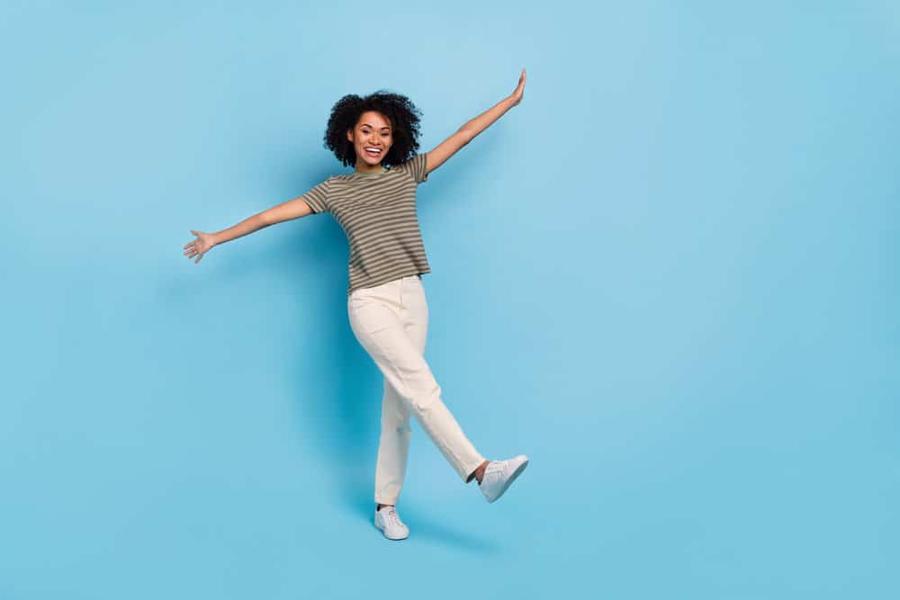 African American female with curls after drying her wet hair with a hair dryer wearing casual weekend clothes.