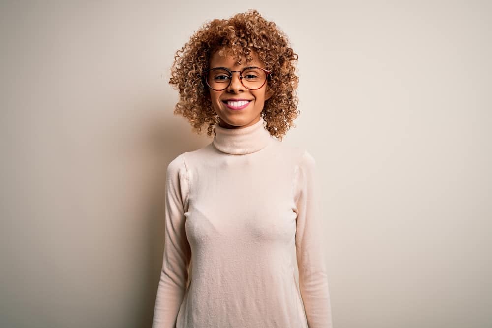 Young African American woman wearing a refreshed darker color due to using blue shampoo on her natural curls.