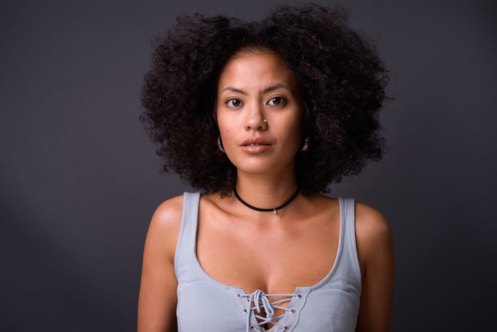 African American woman wearing her hair long with gold earrings and a diamond nose ring. 