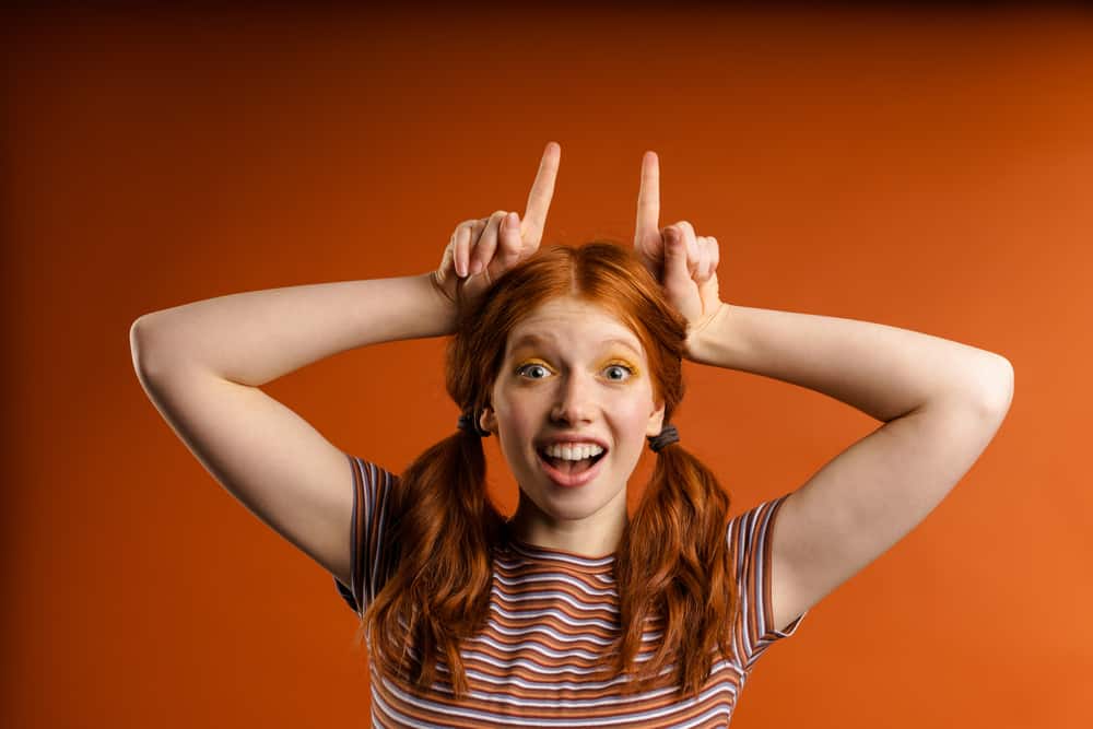 Caucasian female with a bright orange mane after using her hair's natural moisture balance to hydrate her strands.