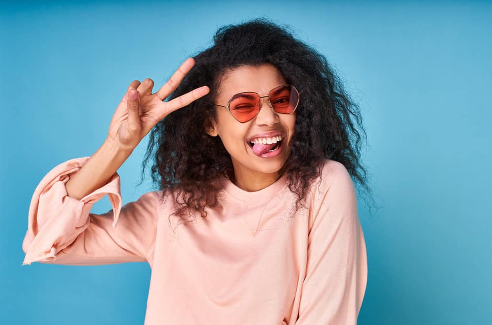 Playful African American female with a wavy-straight hair type after using curl cream to style to thin hair.