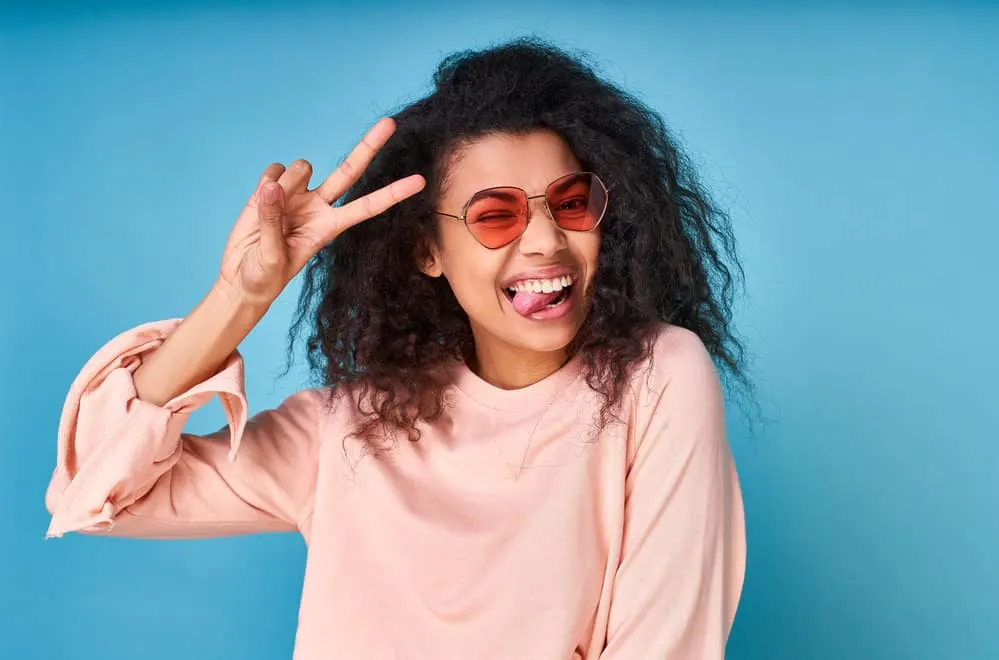 5 Best Products for Fine Wavy Hair: Shampoo, Oil, Gel, & More 1 Playful African American female with a wavy-straight hair type after using curl cream to style to thin hair.