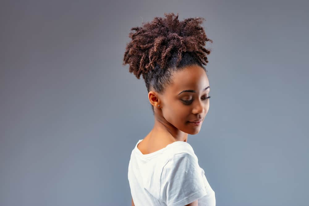 Stylist young woman with light brown tips after bleaching hair with Splat and using a green toner on her curly long hair.