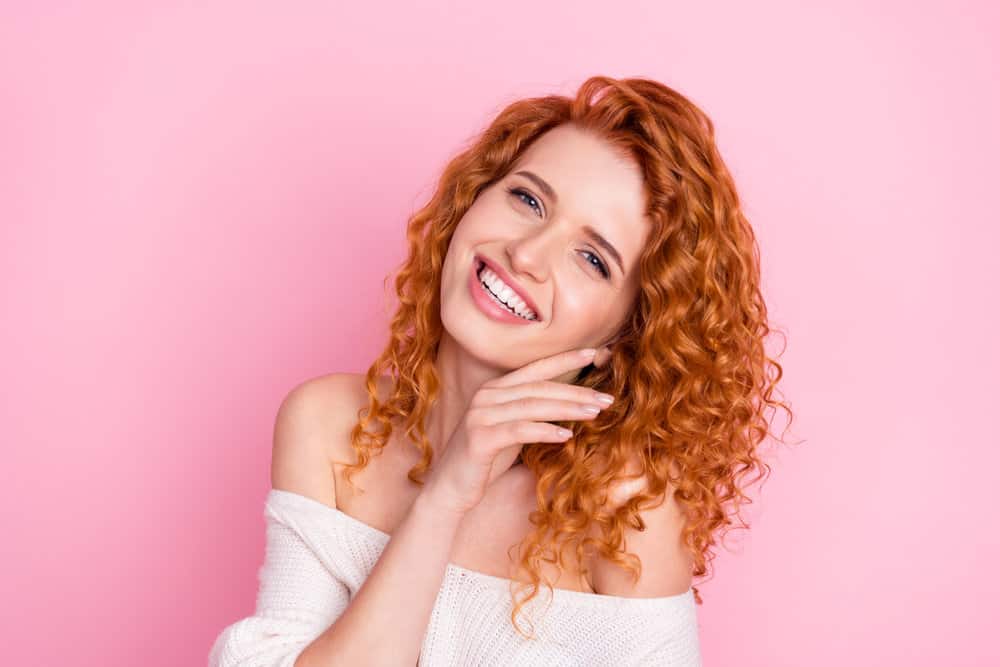 A cheerful young white person with 2C caucasian hair after using Shea Moisture products on her curly hair.