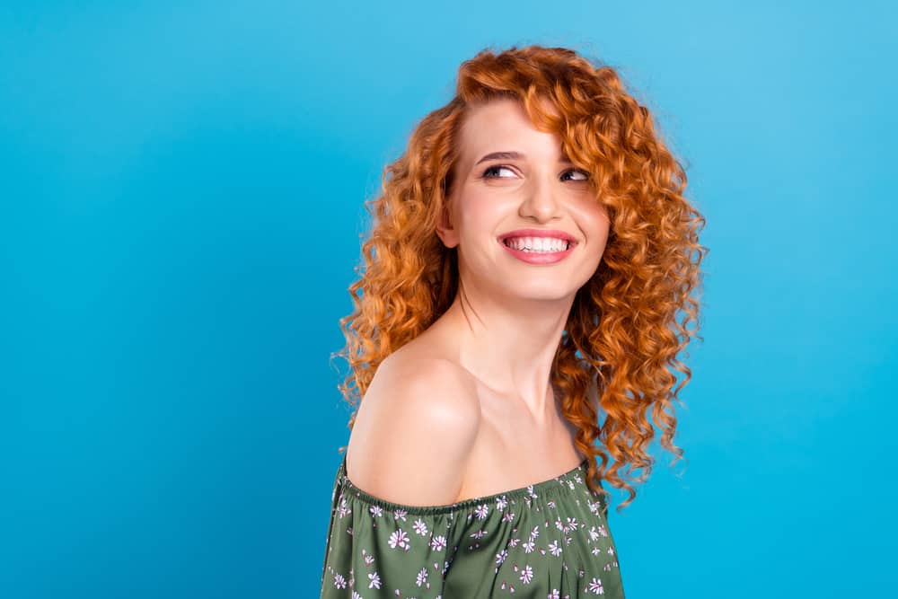 Cute caucasian woman with bleached hair colored with red hair dye wearing a green casual outfit.