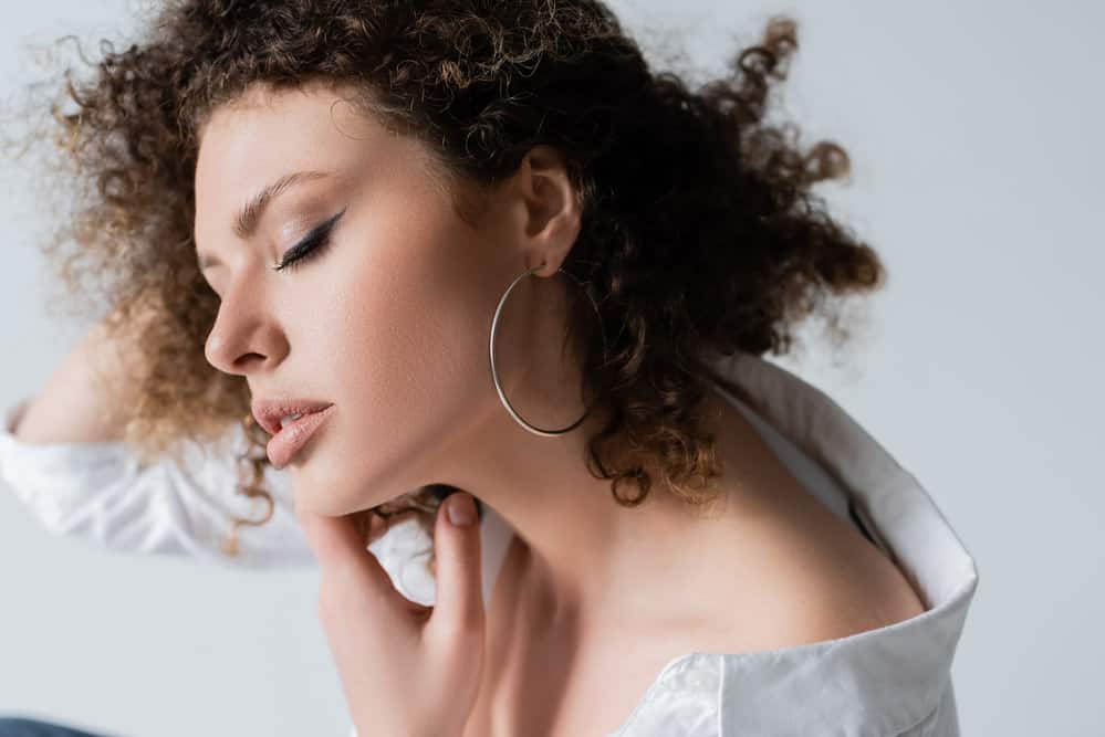 White girl with very curly hair that's a mixture of dark brown and blond hair in a kinky natural afro hairstyle.