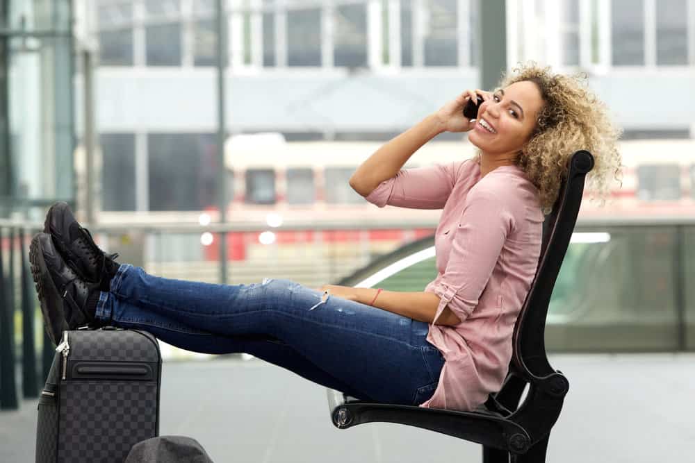 A black girl talking on the phone as she walks down the airport prior to flying.