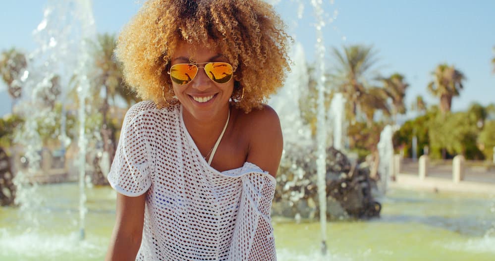 Cute black girl with blonde hair dye on her 4A curly natural hair strands at a beach-front hotel near the ocean water.