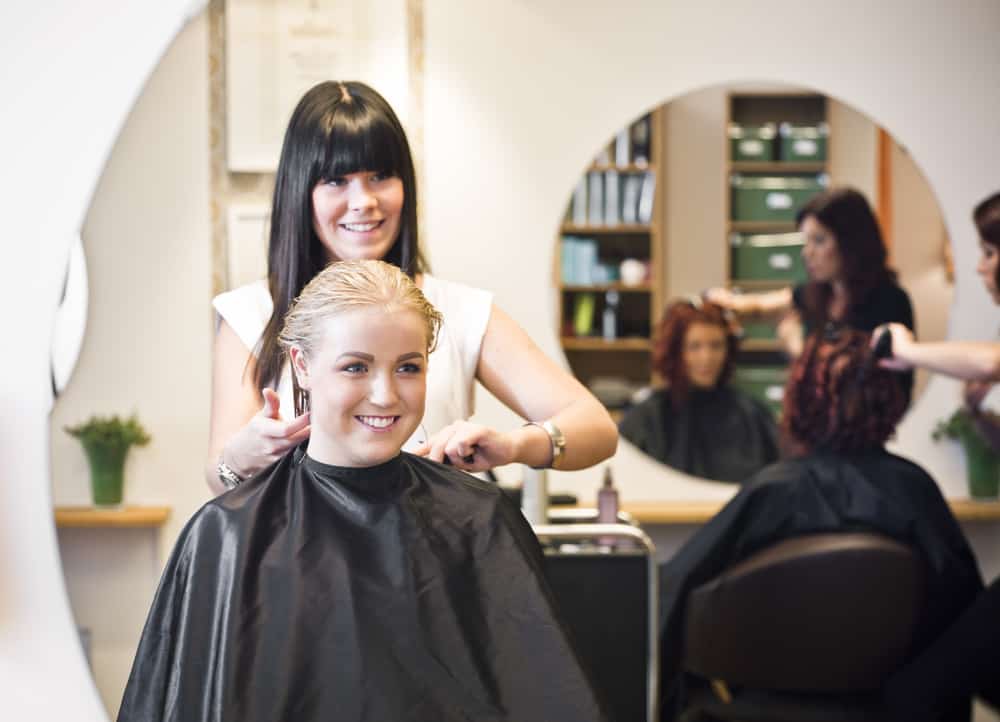 Stylist and client discussing salon prices reported online versus what's available with typical discounts.