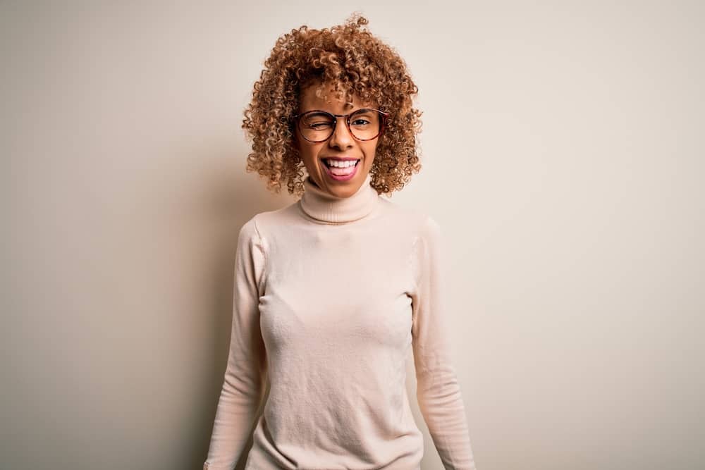 African American lady that dyed her own hair with box dye wearing a brown casual sweater and pink lipstick.