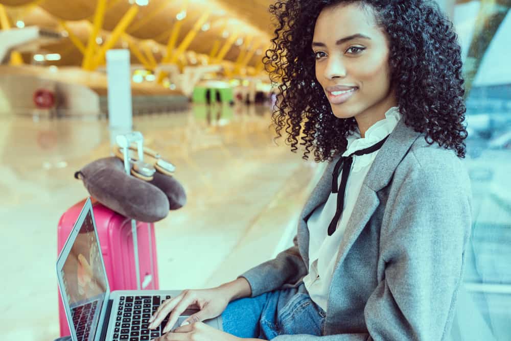 Black female with aerosol hairspray in her carry-on bag preparing to go through transportation security administration.