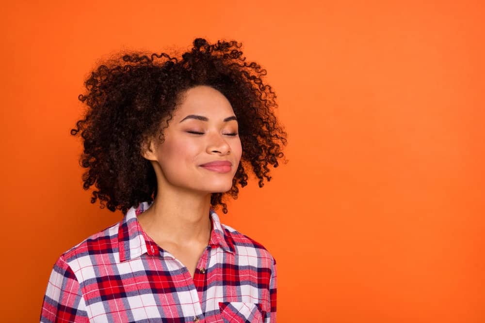 A young African woman with brown hair follicles after applying a DIY hair color kit to her natural hair.