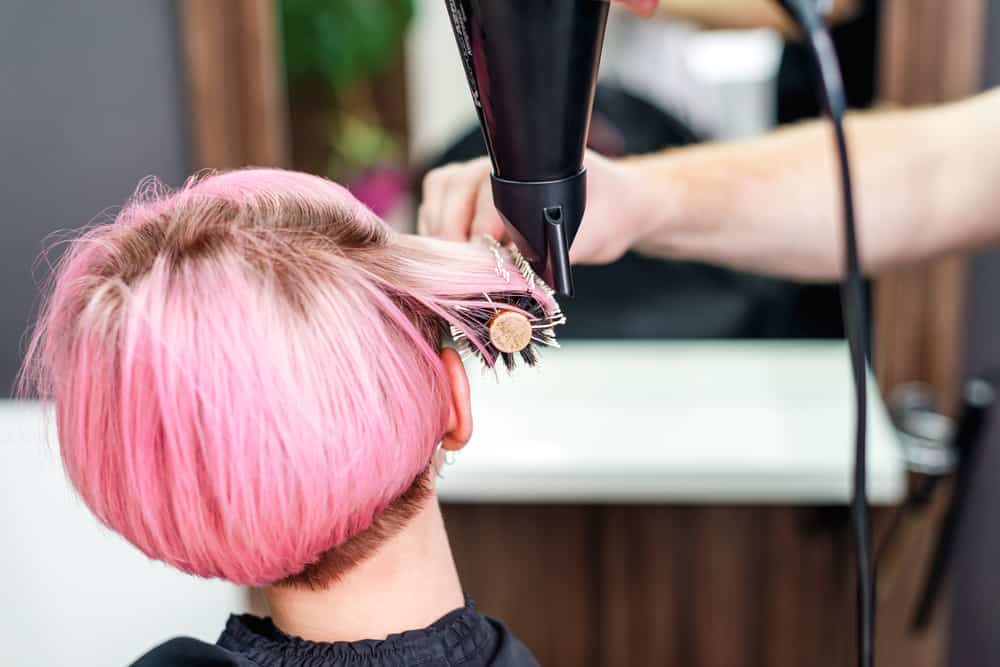 A woman getting a basic blow-dry hair service to following a complete highlight coverage on pink 1C hair type.