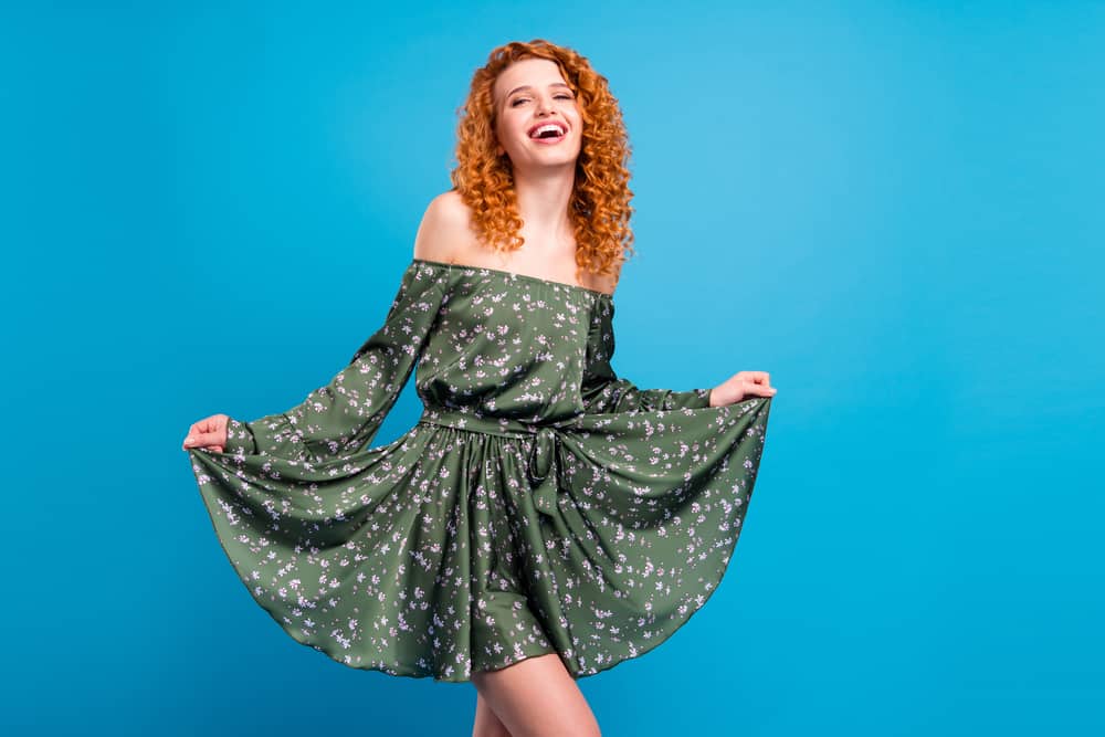 Confident white girl with red hair covered by blonde hair dye, which made her curls lighter.