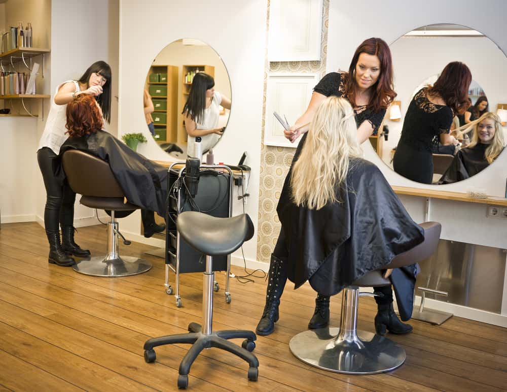 Two barbers hairstyling their clients in signature-style salons.