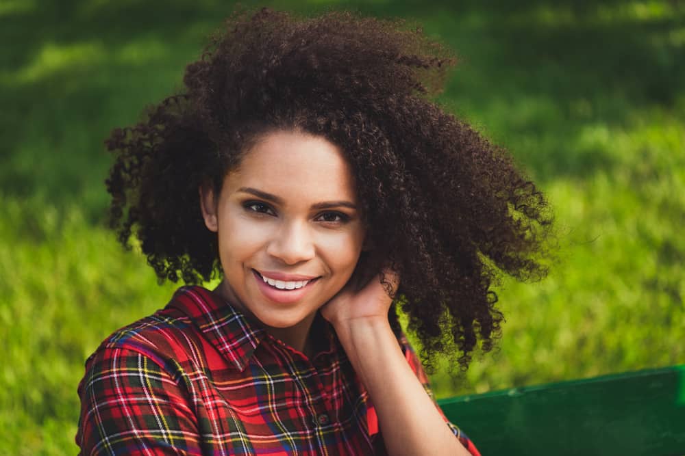 Cute African American female with an oval face wearing a medium-length layered haircut in a curly bob style.