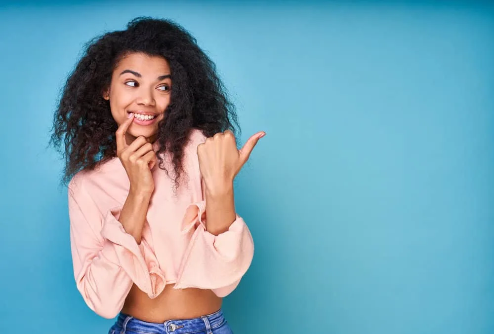 5 Best Products for Fine Wavy Hair: Shampoo, Oil, Gel, & More 8 A beautiful African American female with a curly natural texture after using a texturizing spray on her waves.