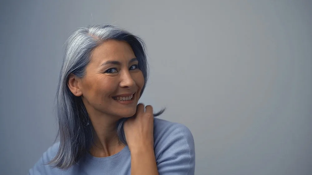 Removing Hair Color to Go Grey at Home: DIY How-to Guide 17 A pretty woman with a great smile and dyed hair is going to return to her natural hair color.