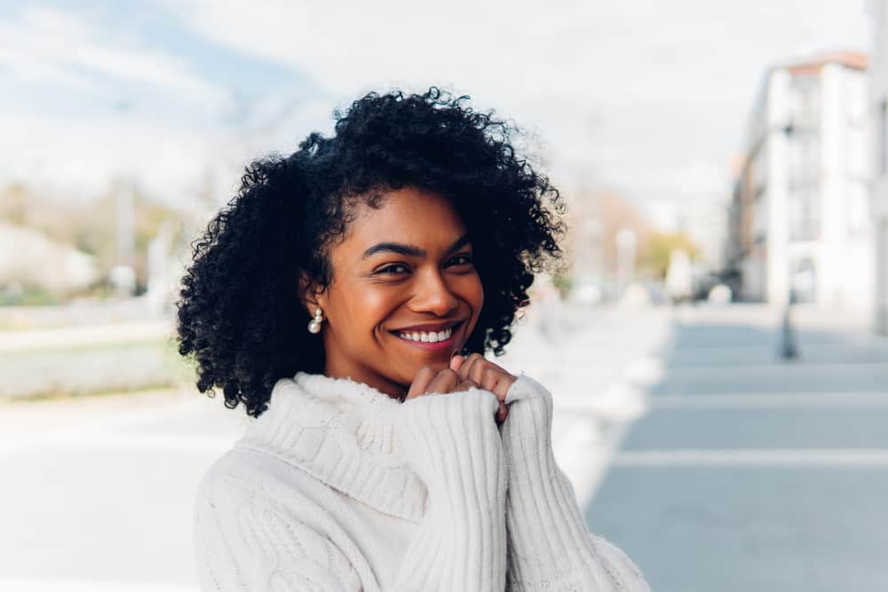 Cute lady with light brown skin tone and a 3C hair type wearing black dye on curls with dark brown natural color.