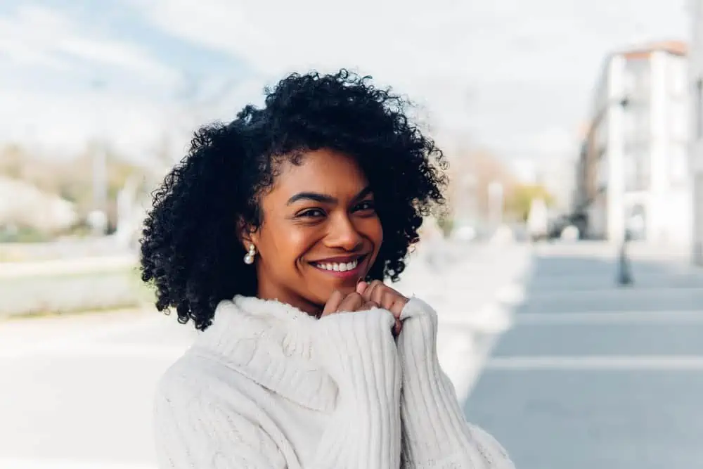Does Dyeing Your Hair Black Damage It or Make It Healthier? 2 Cute lady with light brown skin tone and a 3C hair type wearing black dye on curls with dark brown natural color.