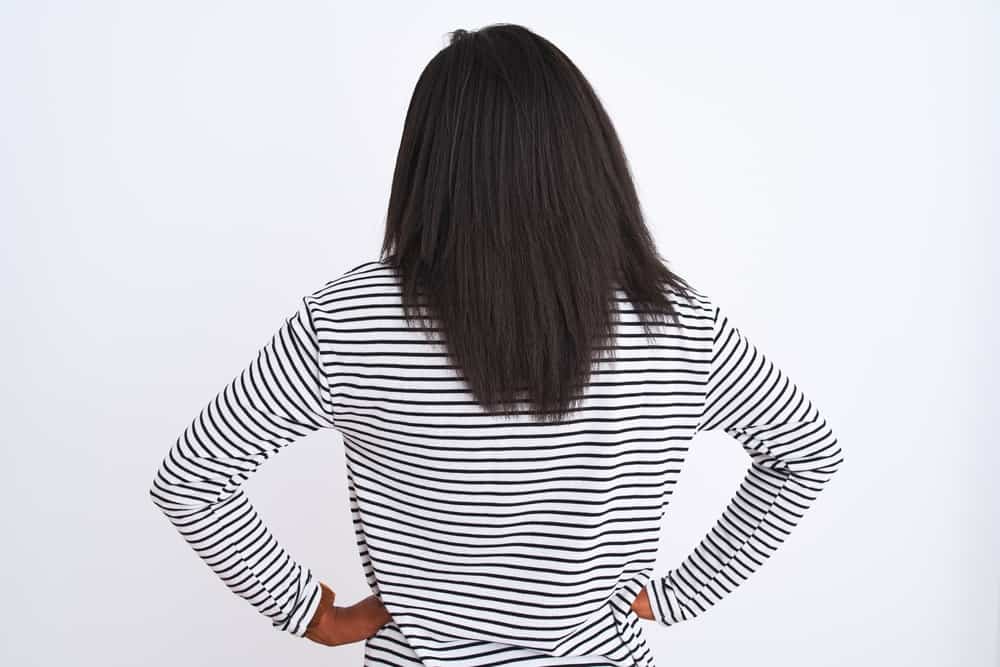 A black lady with type 4A hair shows the results of her hair care routine that has grown her hair.