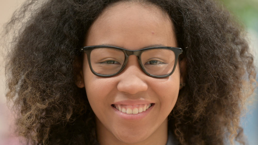 Happy African American female with great smile after leaving the hair stylist with a full fringe haircut.