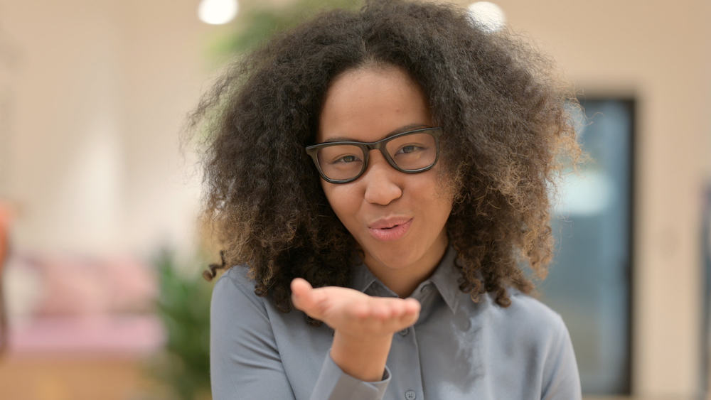 African American female with a layered fringe with longer layers than usual blowing a kiss at the camera.