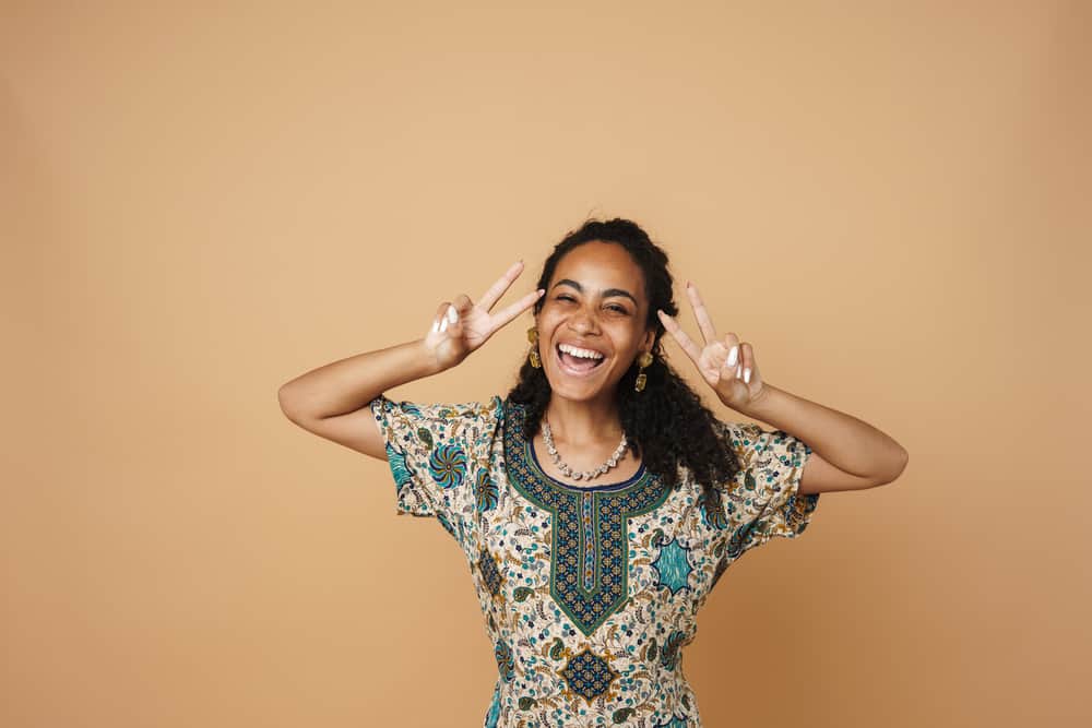 Young black woman wearing a dress with yellow and brassy tones and purple pigments.