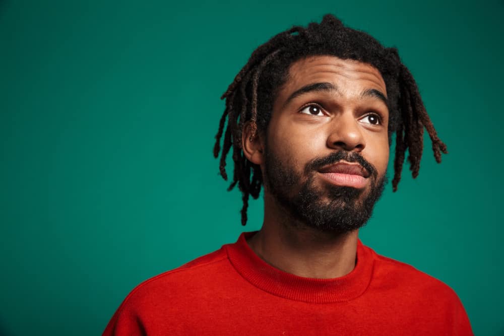 Curious looking black man after dyeing his locs with henna dye and using a hot oil treatment.