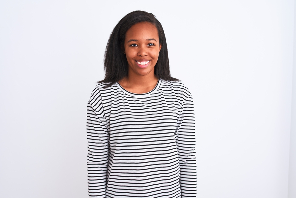 Beautiful young African American girl wearing a black and white long sleeve shirt with silver earrings. 