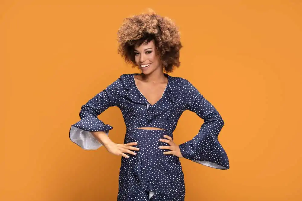 How Long Does Splat Hair Dye Last? How to Make It Last Longer 6 An African American lady posing in a blue and white casual dress with her hair dyed with semi-permanent hair colors.