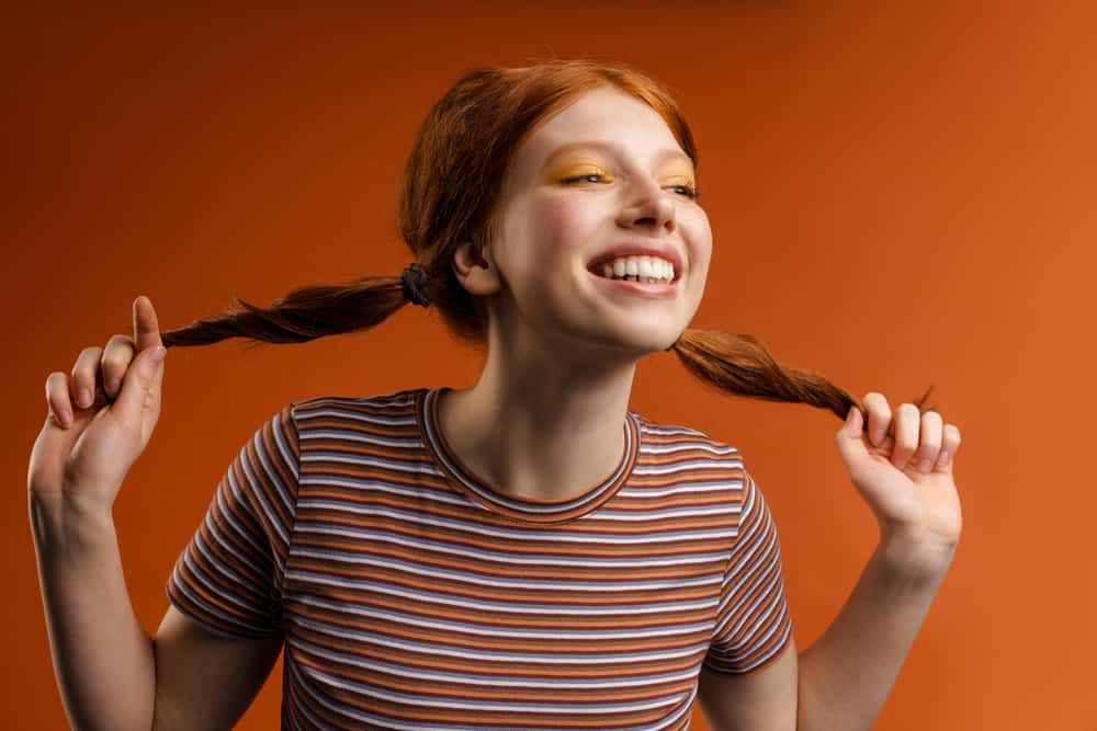 White female with orange hair after bleaching her natural dark ash blonde 1C hair strands.