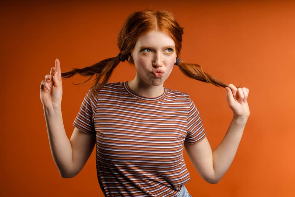 Joyful young woman having fun wearing orange brassy hair after using an ash blonde box dye kit from Walgreens.