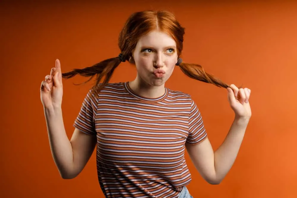 How to Fix Orange Hair With Box Dye: DIY Step-By-Step Guide 5 Joyful young woman having fun wearing orange brassy hair after using an ash blonde box dye kit from Walgreens.
