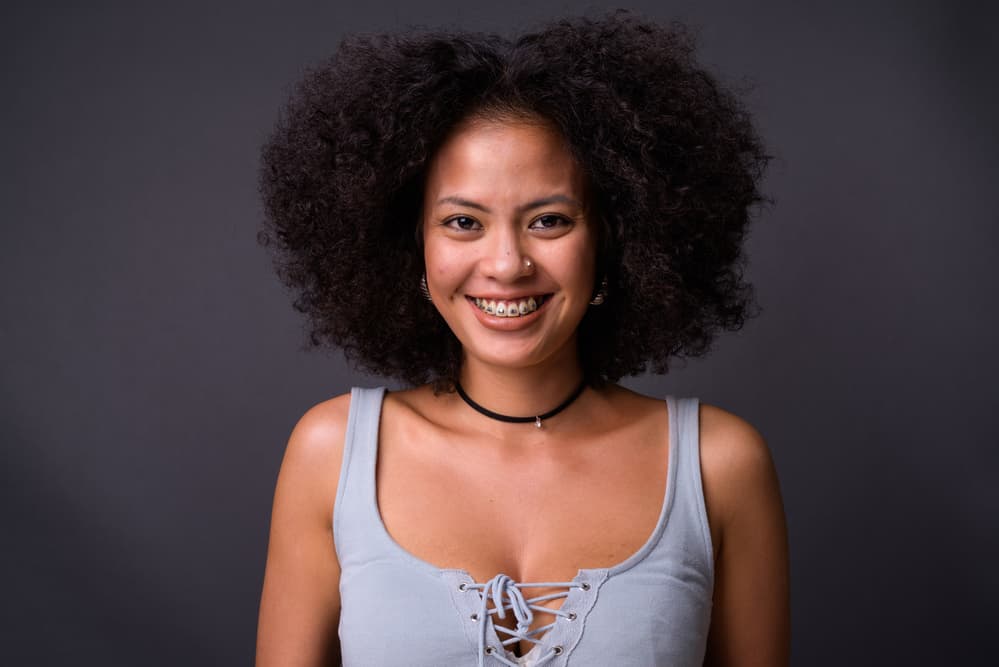 Gorgeous African American female with dark brown hair dye on her cute color-treated hair follicles.