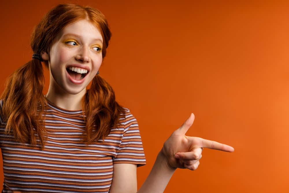 A young lady with 2A straight orange hair wearing her dark hair in a pigtail hairstyle.