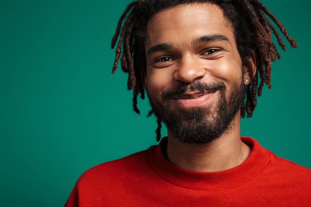 Pleased African American guy after using a hair coloring kit to color the tips of a few dreads.