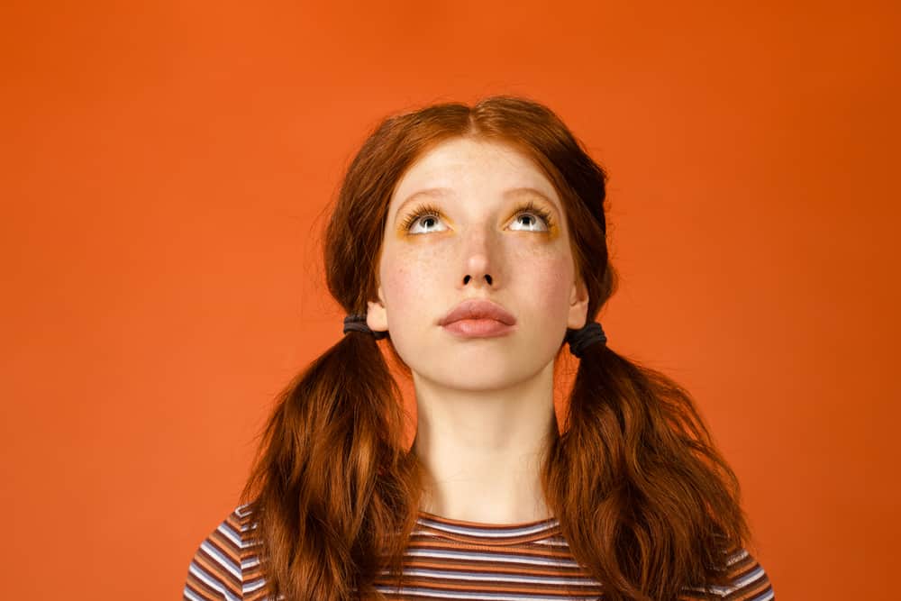 Cute caucasian female with naturally light ash brown colored hair turned orange after using red hair dye.