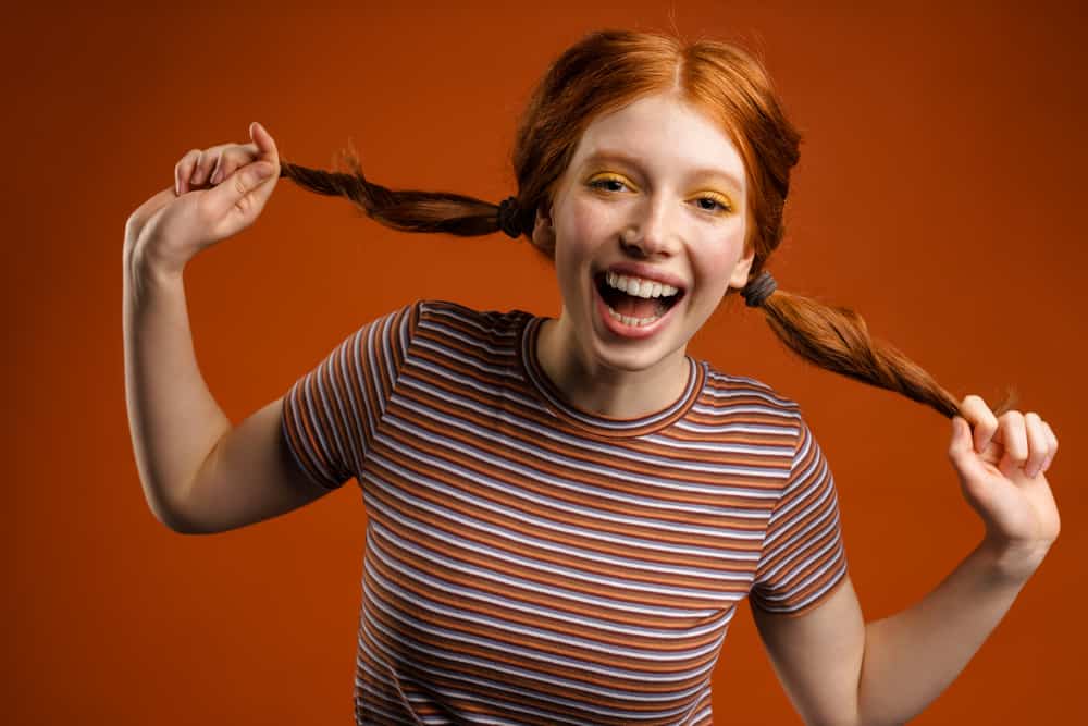 Joyful young female that has 1C hair strands that's a brassy orange color.