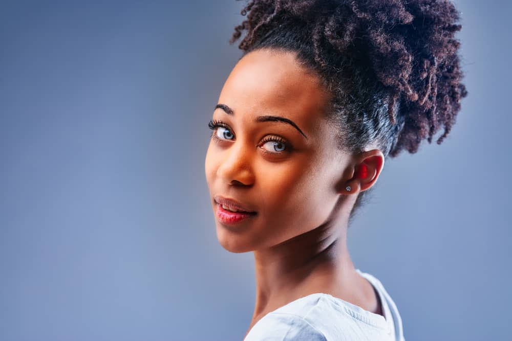 A black girl with a dark brown natural hair color with violet hair tips after using bleach to make her hair lighter.