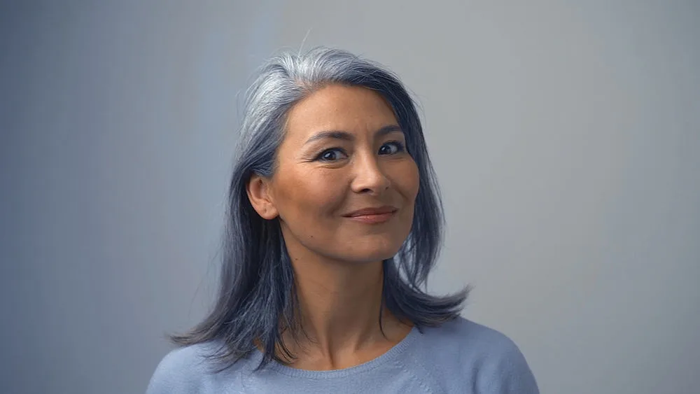 Removing Hair Color to Go Grey at Home: DIY How-to Guide 11 Beautiful mature woman with natural grey hair wearing a hat after removing permanent hair color.