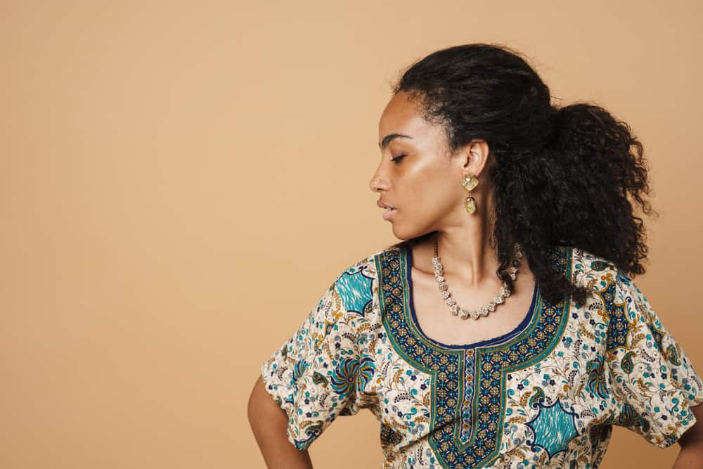 Young black woman with natural curls after using a darker purple shampoo on darker hair.