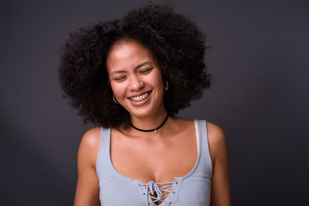 Black girl with a great smile after getting a root touch-up on her jet black darker roots.