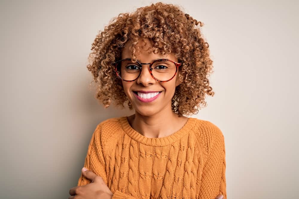 Black lady wearing brown curls after using a mixture of semi-permanent hair dyes to create a dynamic, vibrant color.