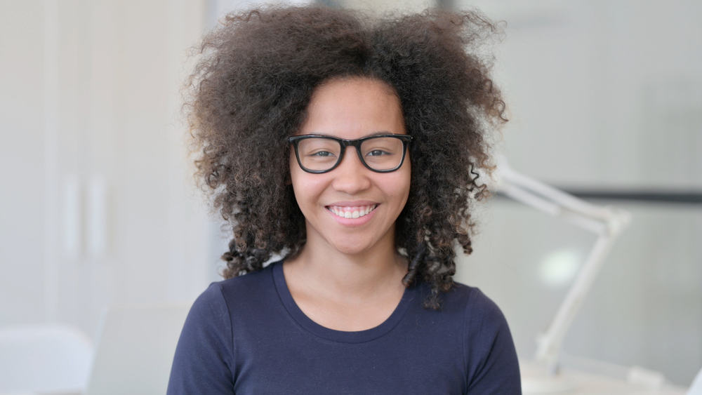 Cute African American female with a voluminous wolf haircut and an oval face shape styled with curl cream.