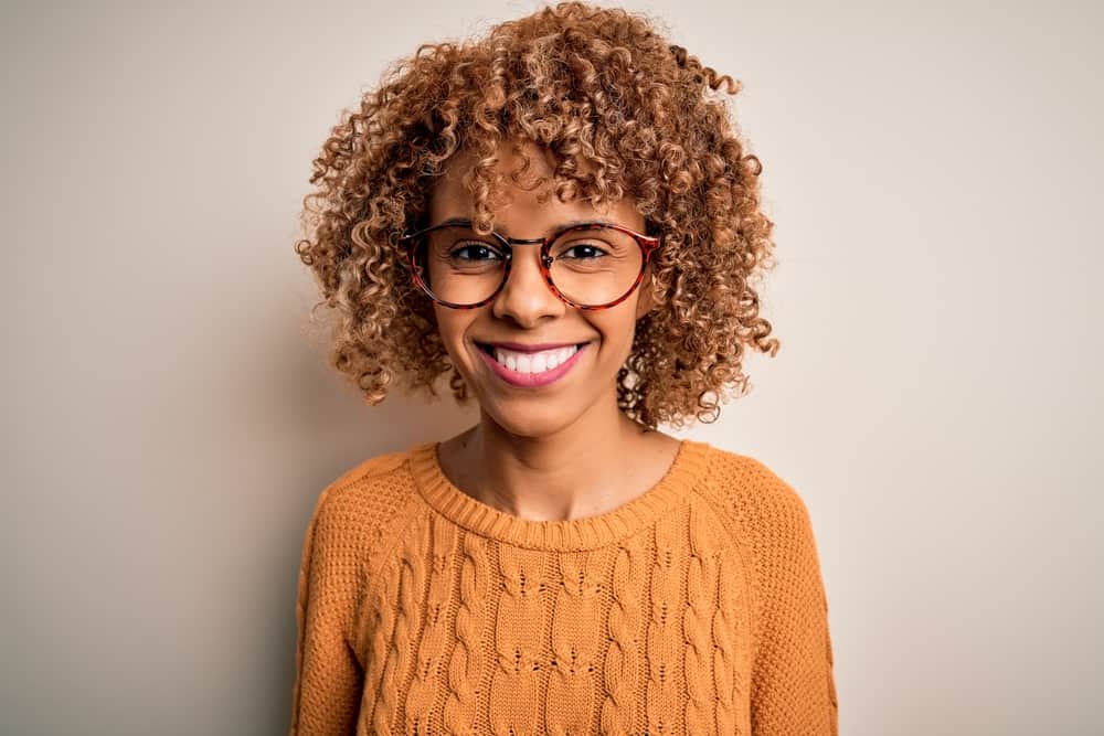 African American female wearing a semi-permanent hair color on naturally curly color-treated hair strands.