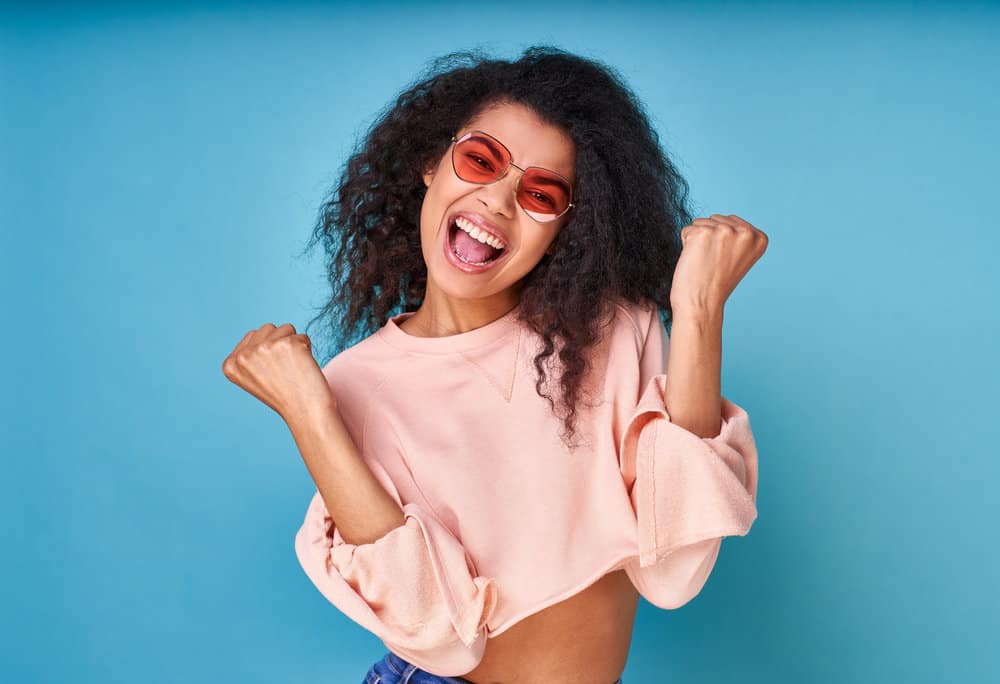 Joyful black lady with thicker hair after using a volumizing deep conditioner and coconut oil.